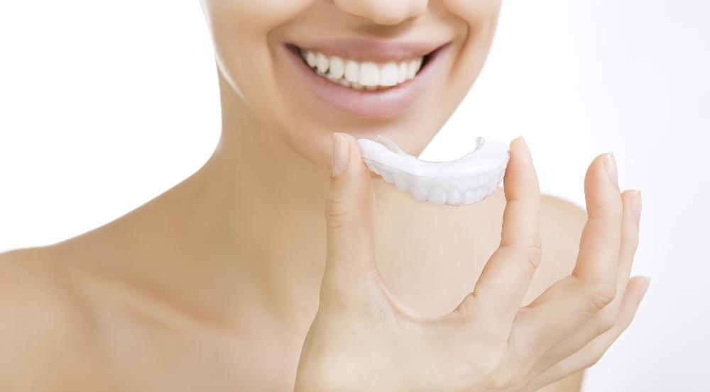 woman holding clear plastic aligner | clear aligners st paul mn