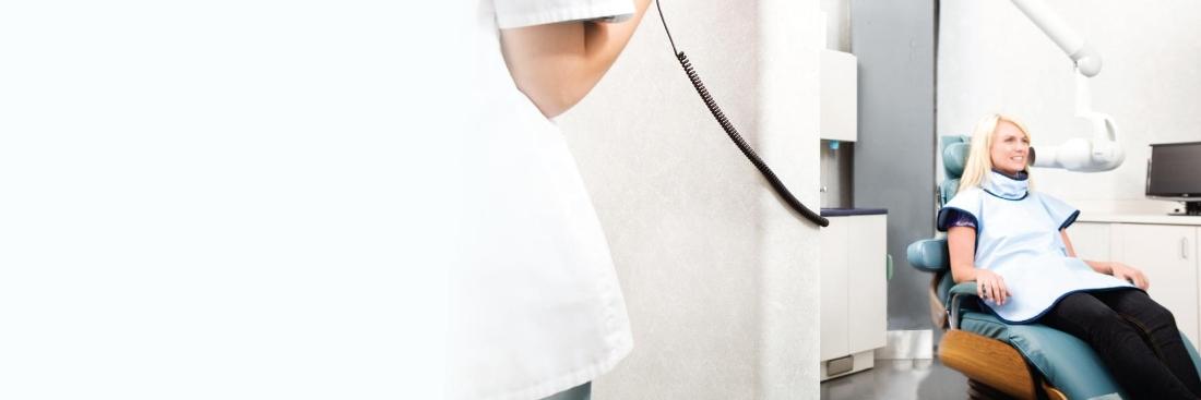 blonde woman waiting for dental x-rays in dental chair with blurred dentist in foreground