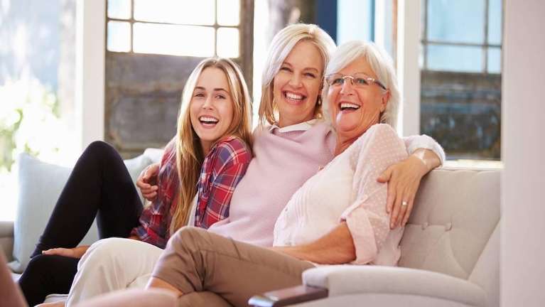 mom, daughter, and grandmother smiling on the couch in Saint Paul