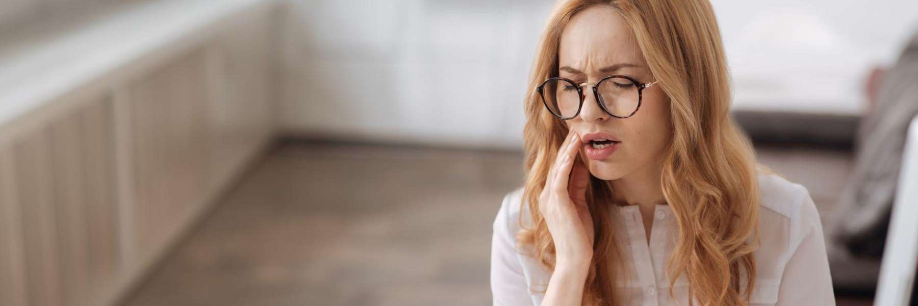 Redhead woman holding her jaw in pain, saint-paul mn